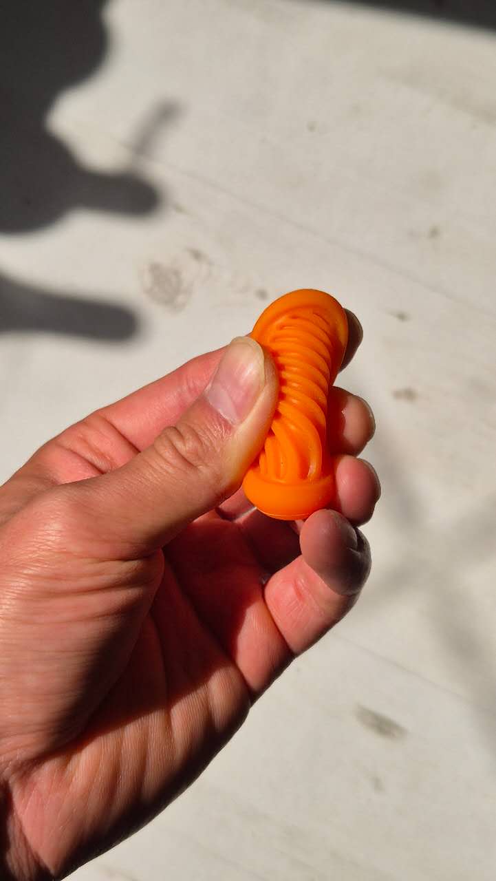 Hand holding an orange silicon fidget toy against a light background