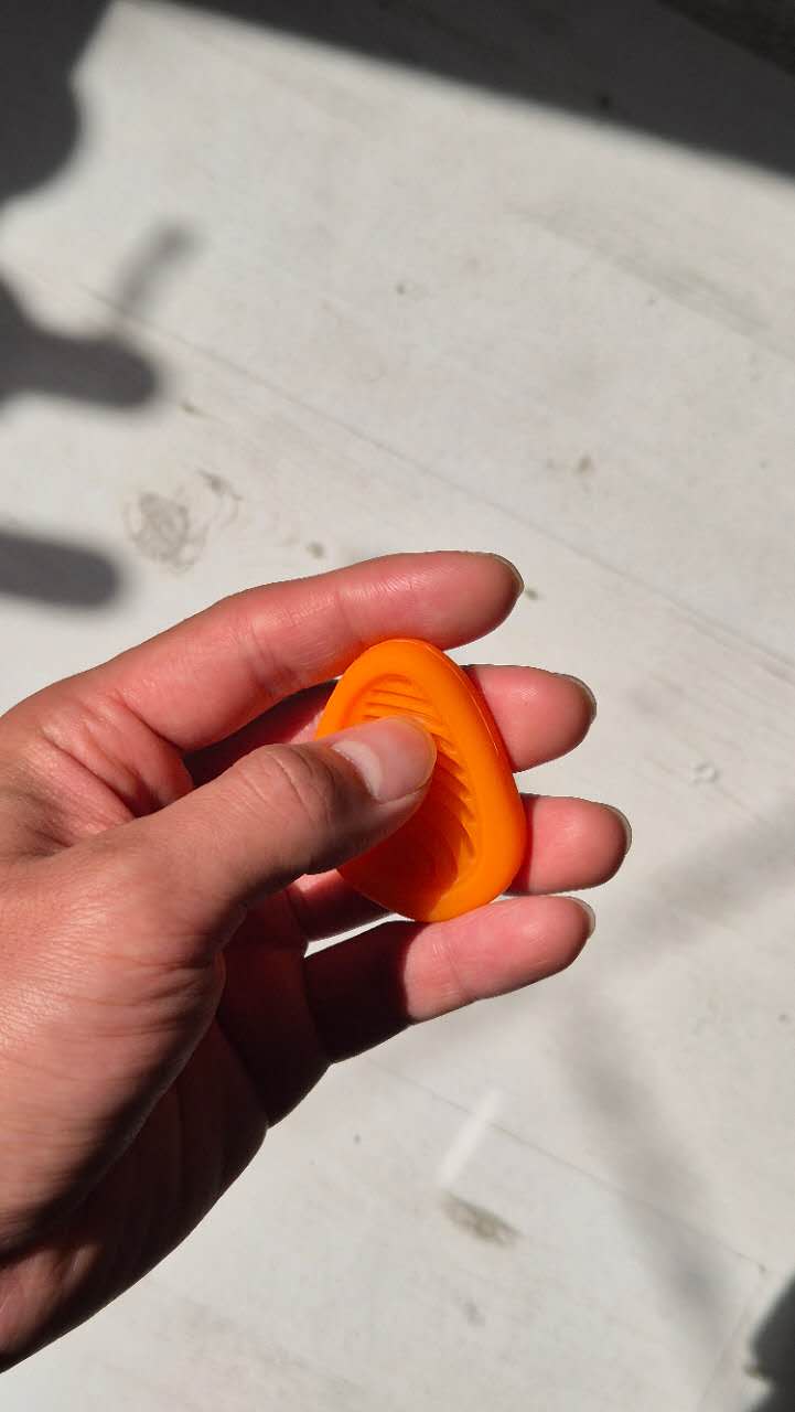 Hand holding a bright orange silicon fidget toy against a light background