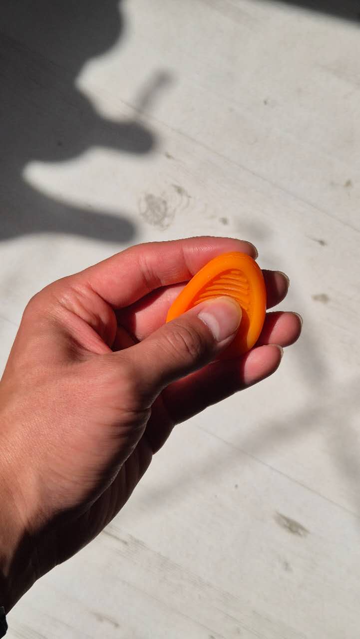 Hand holding an orange silicon fidget toy against a light-colored surface