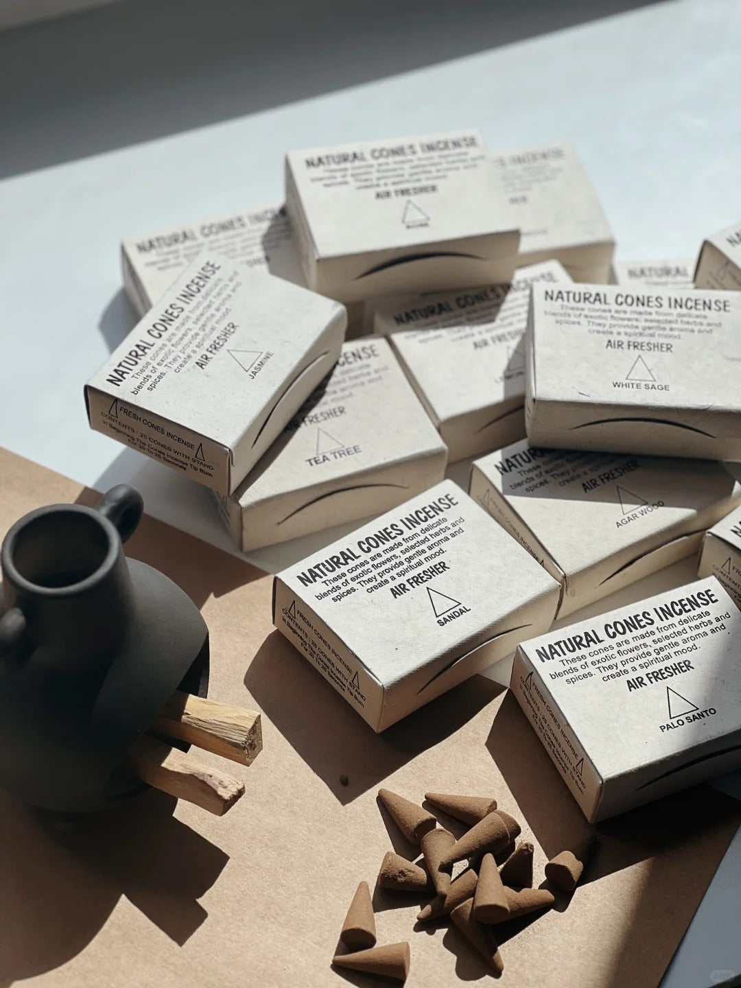 Incense cones and packaging on a light surface with a dark vase.